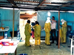 © Tim Shenk/MSF Brett Adamson, coordinateur pour MSF aide un soignant qui se prépare à entrer dans la zone à haut risque du camp ELWA 3 à Monrovia (Liberia) 