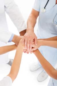 Close-up Photo Of Doctors Stacking Hand With Coworkers