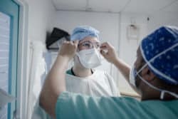 Un collègue aide Julie infirmière en USIC à s'équiper avant de rentrer dans une chambre. Un collègue aide Julie infirmière en USIC à s'équiper avant de rentrer dans une chambre.
