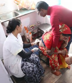 Cette femme suivie pour un furoncle très douloureux au bas du dos, est soutenue par son mari pendant que Son nettoie avant de refaire le pansement