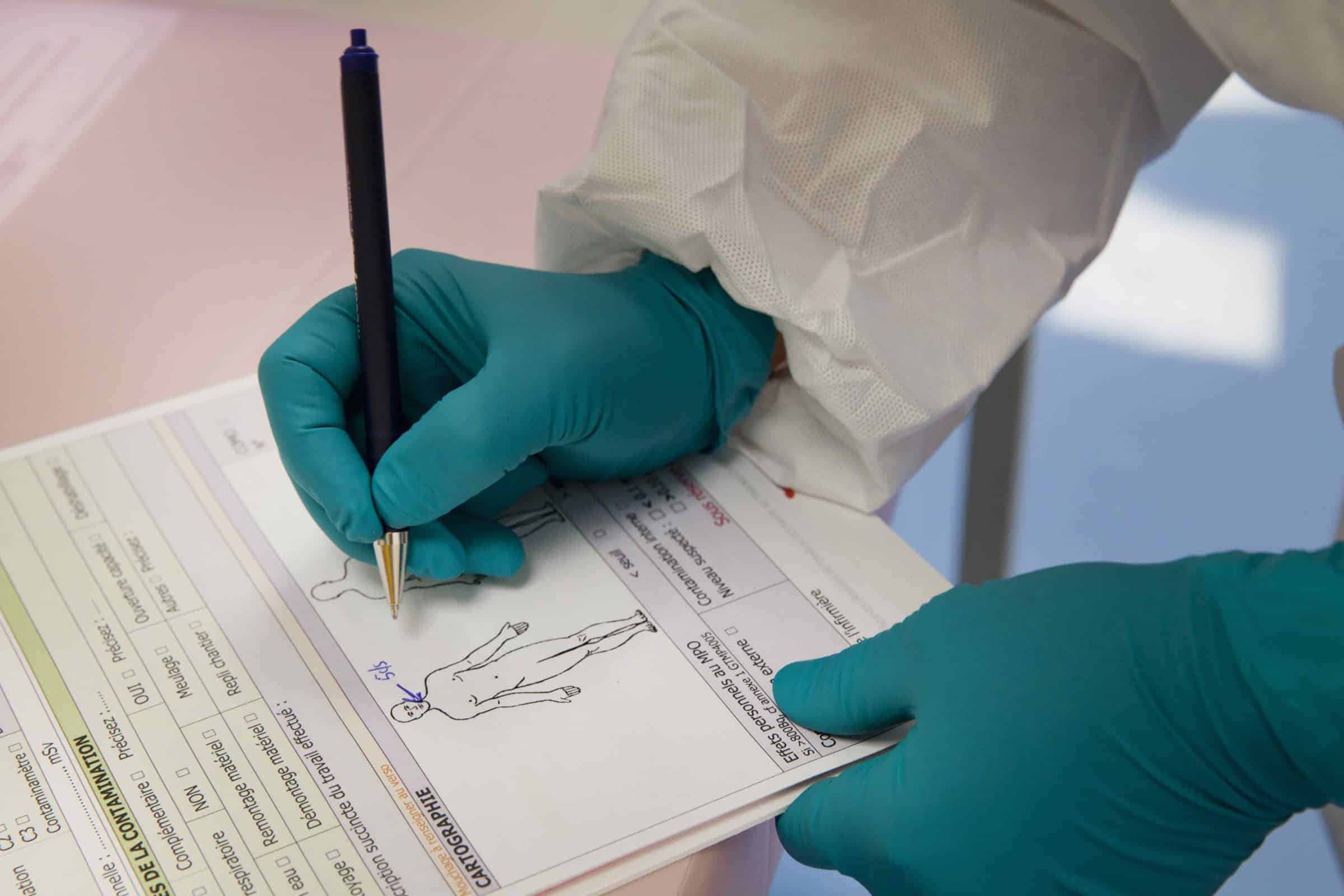 Catherine Martin, infirmière, note la localisation de la particule radioactive sur le corps du travailleur.
