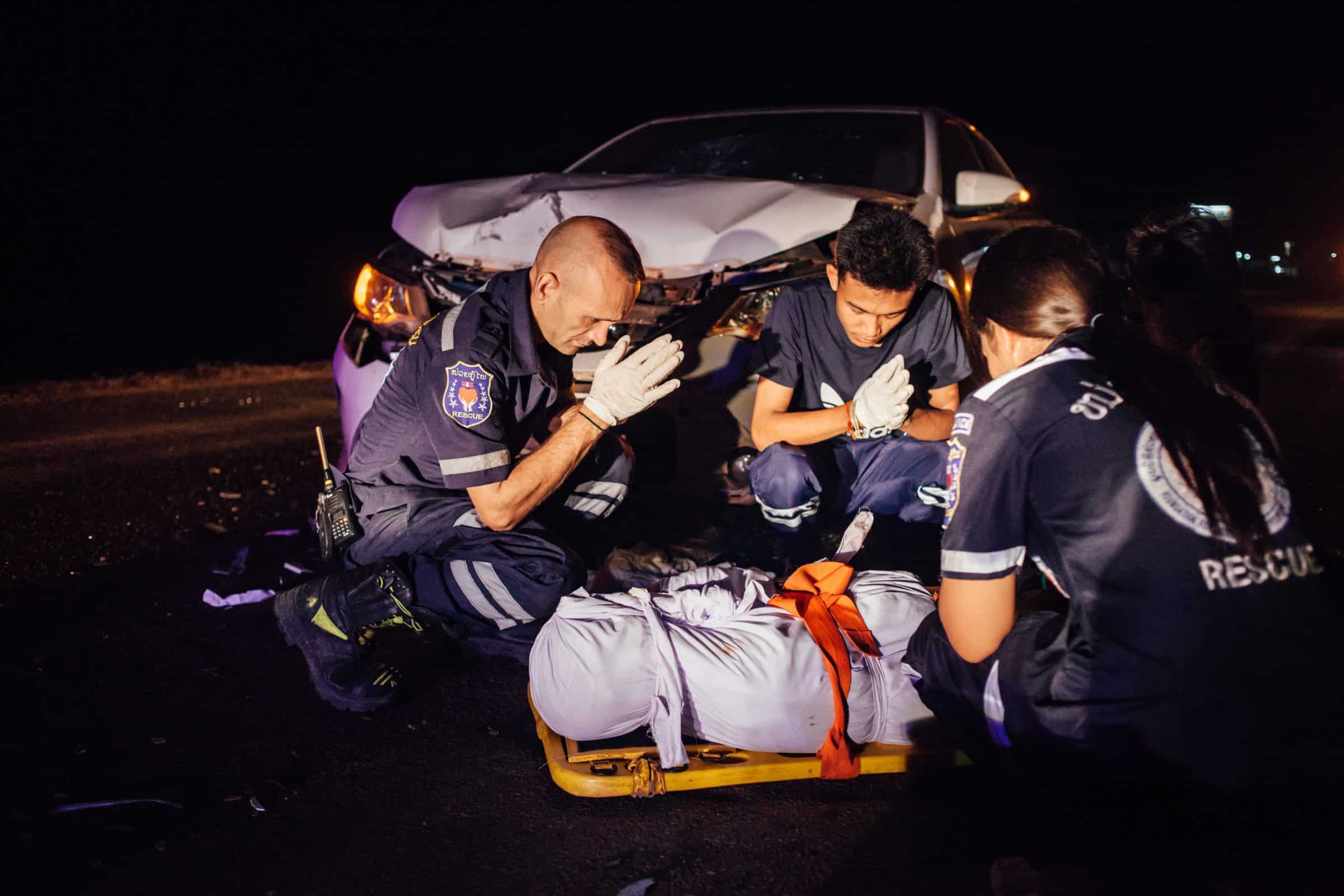 Une équipe de Vientiane Rescue fait une prière après avoir enveloppé le corps sans vie d'un accidenté de la route dans un tissu blanc Une équipe de Vientiane Rescue fait une prière après avoir enveloppé le corps sans vie d'un accidenté de la route dans un tissu blanc