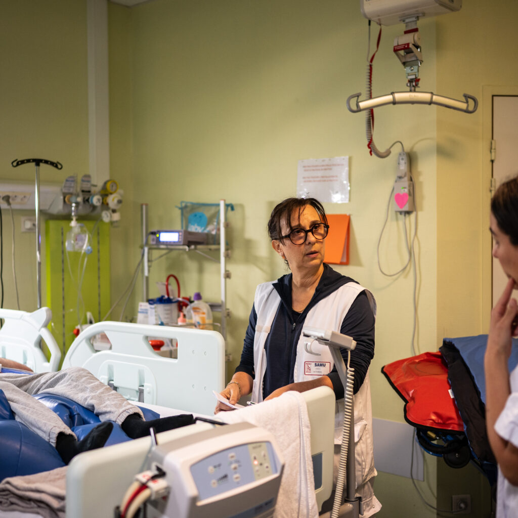 Les infirmiers du SMUR peuvent sortir seuls avec un ambulancier pour une T2IH, un « transport secondaire interhospitalier », pour des patients qui nécessitent une surveillance infirmière. « C’est cadré, les patients doivent être stables » et la régulation reste toujours joignable. Ici, Véronique Bénat récupère les transmissions de l’équipe médicale d’une structure d’accueil de personnes en situation de handicap. © Bastien Doudaine